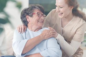 Old lady in wheelchair with carer happy knowing her care home uses an efficient care management solution