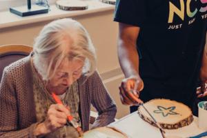 Volunteer from NCS Young People painting with an older lady at Borough Care’s Lisburne Court  
